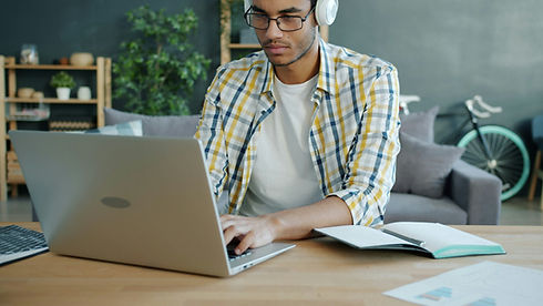 A man with headphones and glasses sits at a desk
