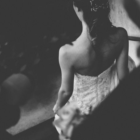 A bride descends the stairs, her lace wedding dress beautifully captured in black and white, evoking timeless elegance.