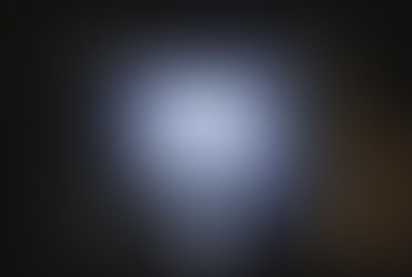 A clear light bulb sits atop an open book, illuminating the text. The pages are slightly curved with visible text on pages 208 and 209.