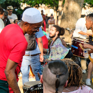 a gathering of musicians and people having a good time, some standing some sitting all smiling and enjoying the present