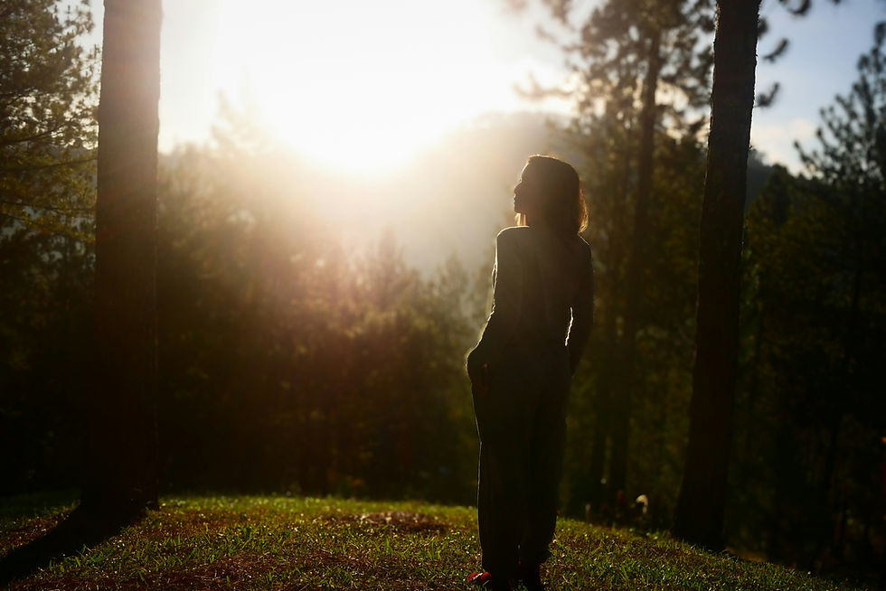 A woman watching the sunlight in a forest.