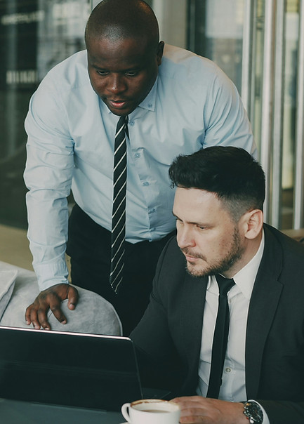 Two businessmen in suits reviewing work together on a laptop in an office