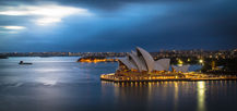 Sydney Opera House illuminated at dusk over the water in Australia.
