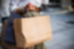 A person holds several shopping bags on one arm