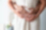 Close-up of husband and wife's hands gently cradling pregnant belly