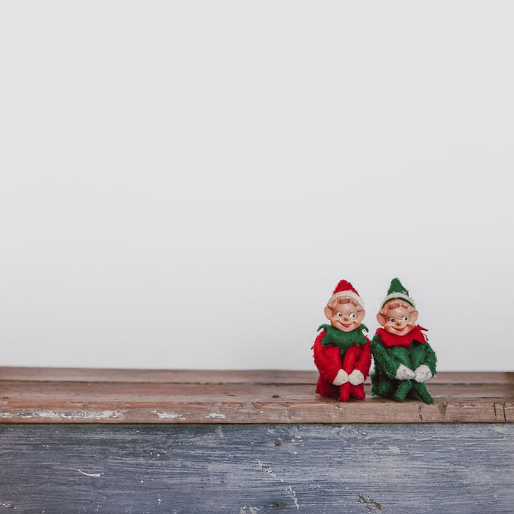 An image ofSmall Christmas elf statues seated to one side of a bench.
