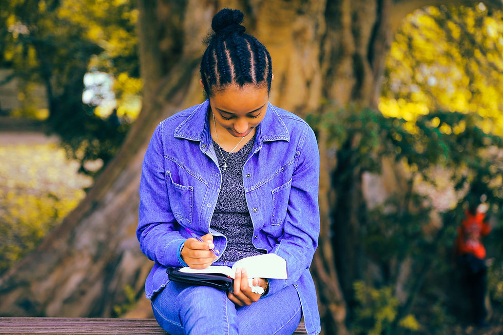 Young woman writing in a journal outdoors