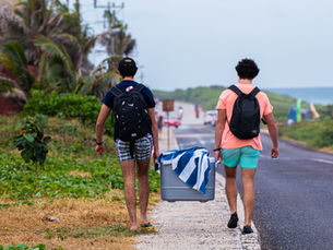 Two Latino beachgoers walking down a sandy road
