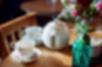 two china tea cups, tea pot on a kitchen table.