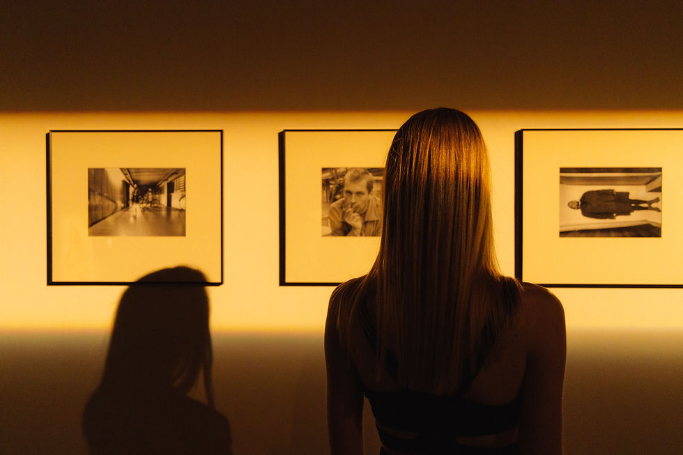 Three photos being viewed by a woman and child in a gallery