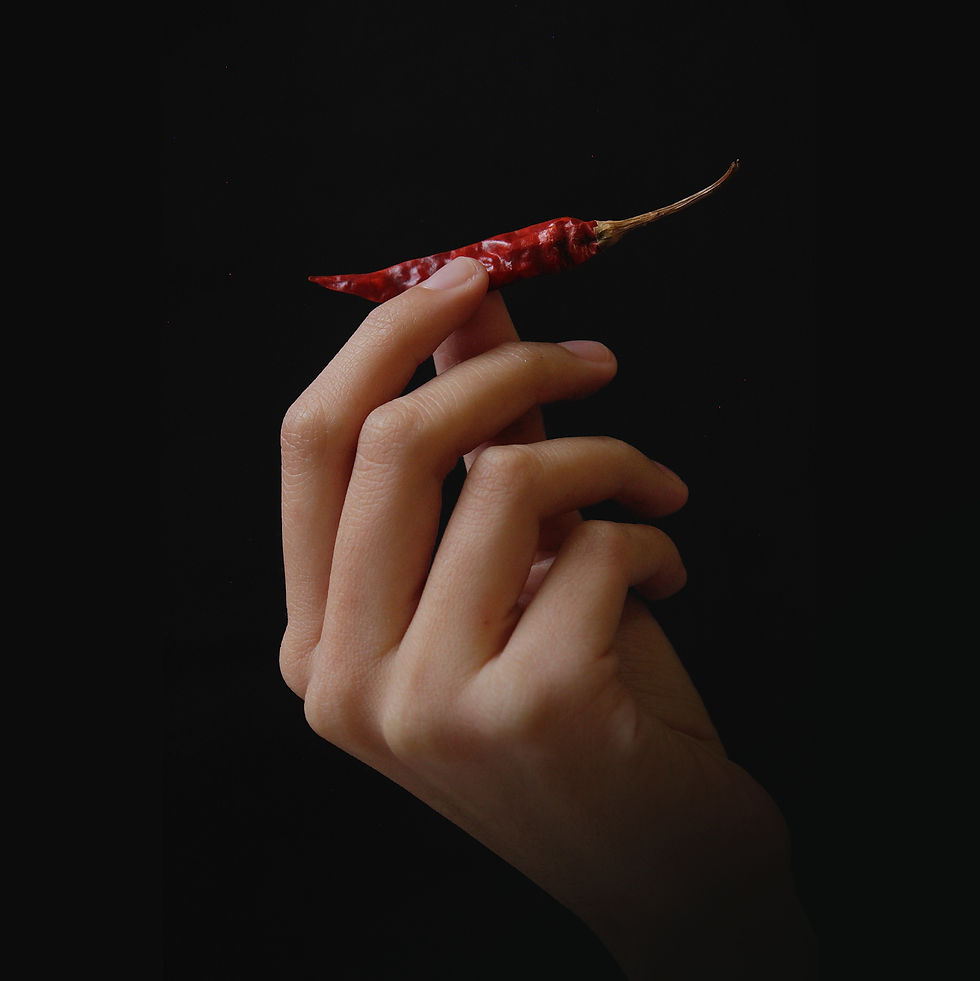Person holding a chili and preparing to eat spicy foods to increase metabolism and burn more fat