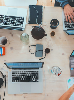 Bird'seye view of a work table. Two open laptops with one person typing