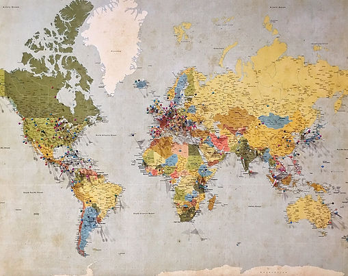 World map with push pins inserted in multiple countries.