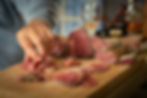 Man picking up salami from wooden board