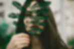 A beautiful Eurasian woman holding a green fern leaf in front of her face