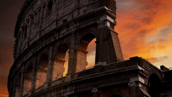 The sun sets with orange and red colors on the Roman Colosseum.