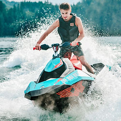 Les montagnes majestueuses du Jura servent de toile de fond à un pilote de jetski qui s'élance avec grâce sur les vagues.