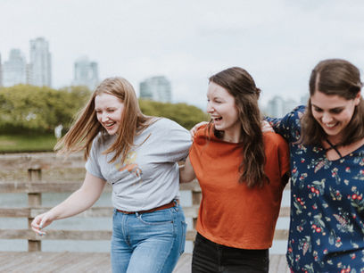 Three women embracing as they walk forward arm in arm laughing and helping each other get through job loss