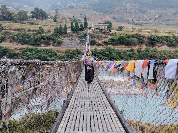 Attraversamento del ponte sospeso di Punakha decorato con bandiere di preghiera in Bhutan.