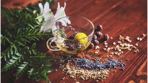 Ayurvedic herbs, flowers and a glass of herbal tea on a wooden table