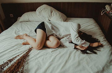 Woman laid on bed feeling ill. Get well with Ayurvedic health coaching from AyurLife UK