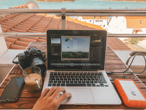 An open laptop with a coffee mug and camera besides it.