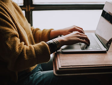 Image of someone sat at a table typing on a laptop