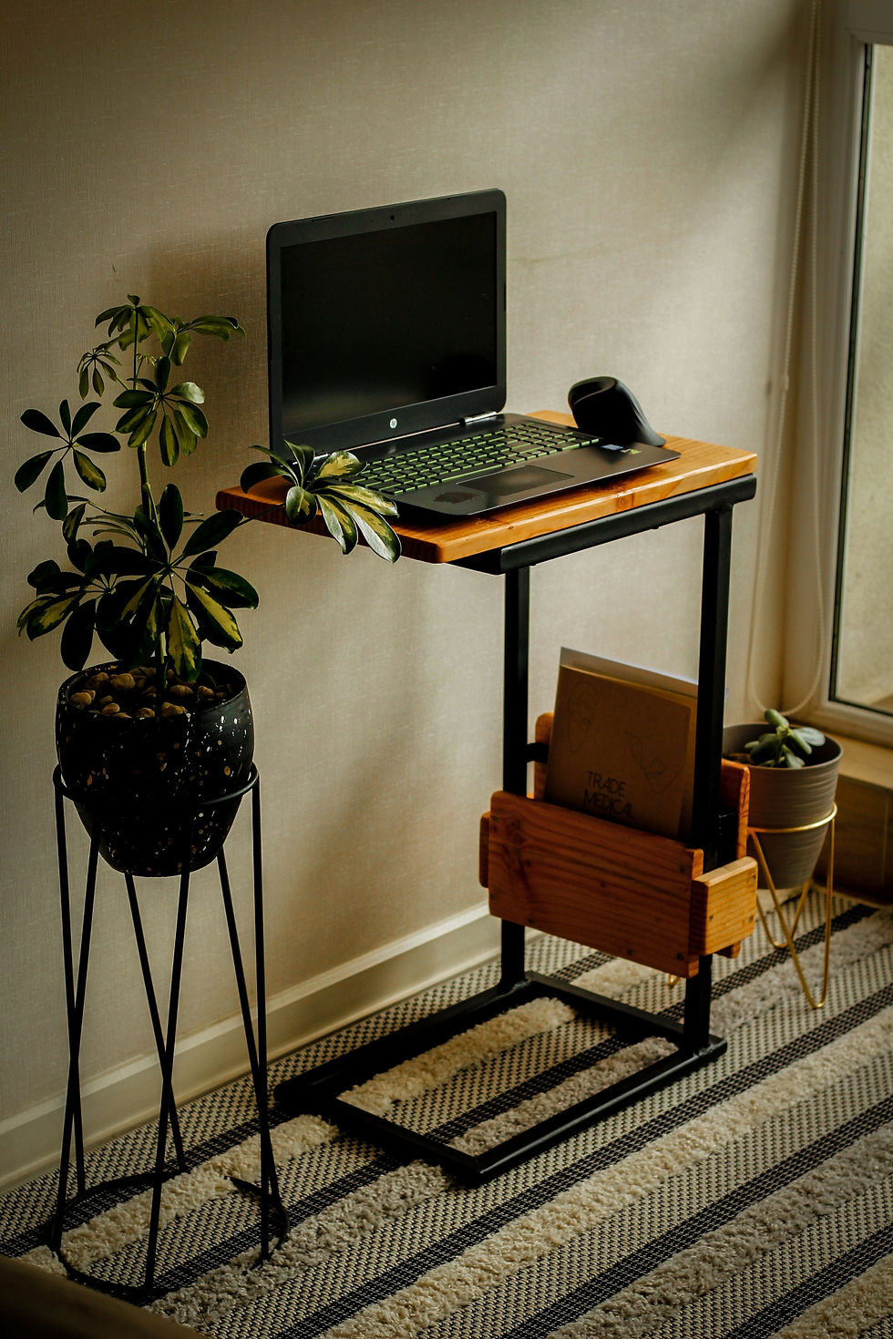 Bureau réglable moderne installé dans un espace de travail à domicile, avec plateau en bois clair, structure métallique noire et écran d’ordinateur posé à hauteur des yeux.