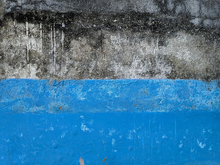 Weathered concrete wall with peeling blue paint and dark staining
