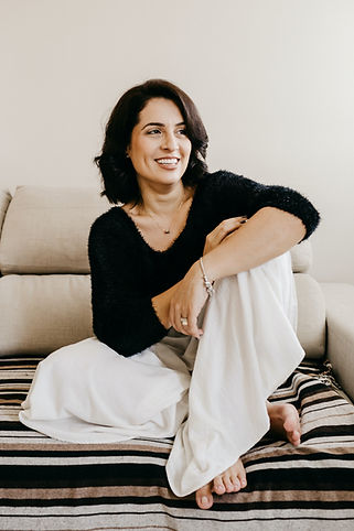Image by Jonathan Borba of dark-haired woman in black and white sitting on a beige and black couch