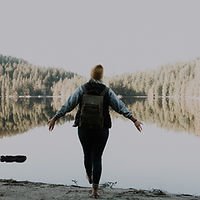 A woman arms outstretched looking out at a lake