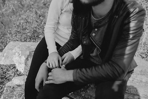 Man and woman sitting together on rocks holding hands