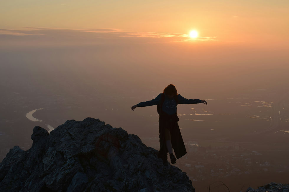 Person with arms open wide on a mountain top at sunrise