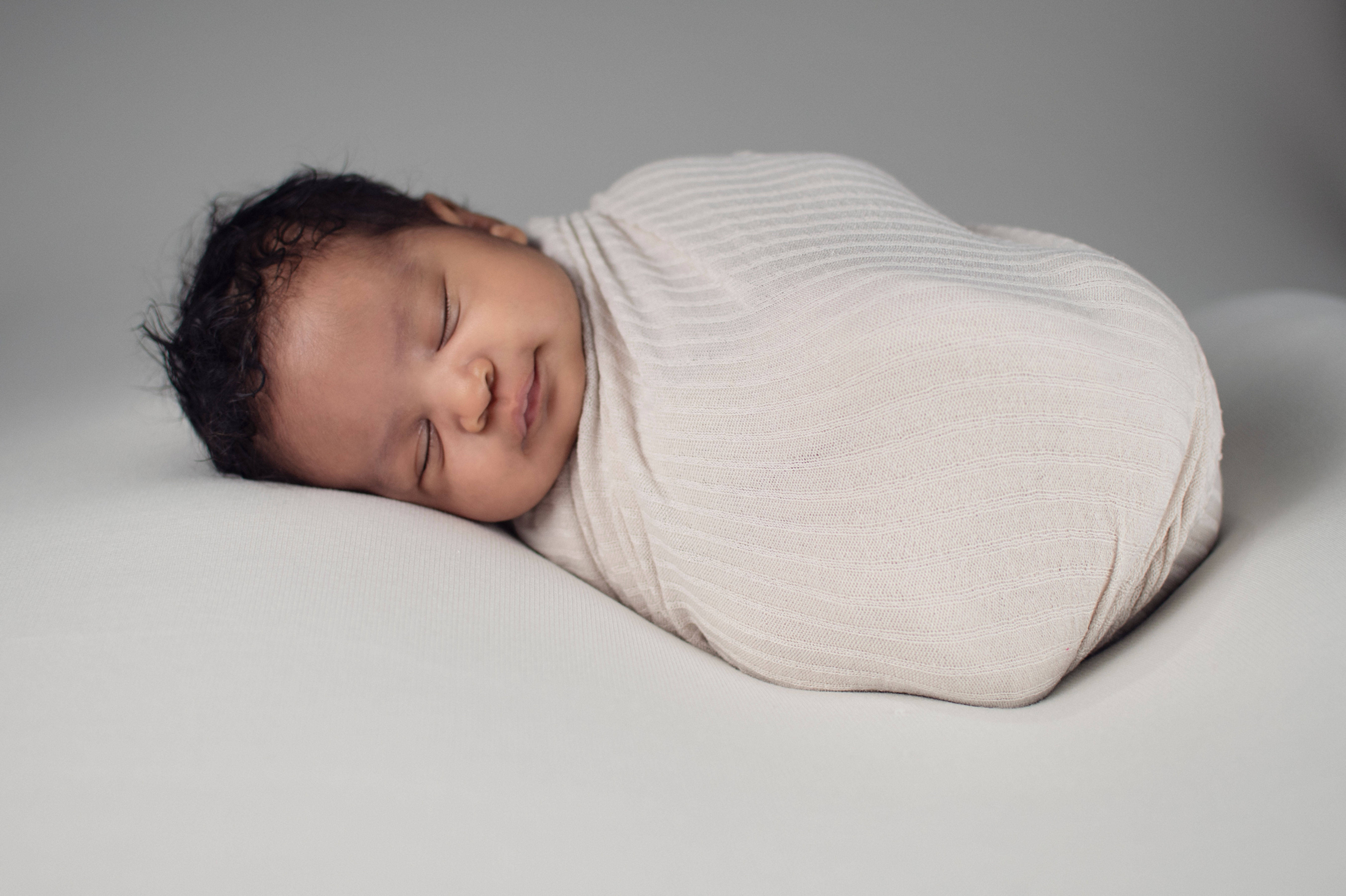 Peacefully sleeping baby wrapped in a light blanket — representing the calm that comes with gentle sleep support.