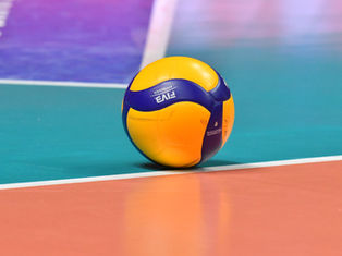 A yellow and blue volleyball with "FIVB" text rests on a colorful court with orange, teal, and purple sections, creating a vibrant scene.