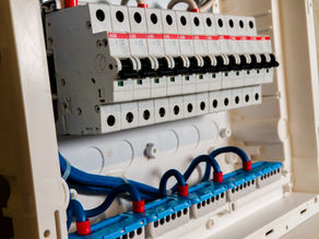 Row of ABB circuit breakers inside an electrical panel, with red labels and black switches neatly lined up.