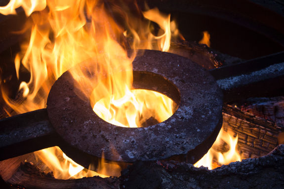 A metal piece is heated in the flames of a forge in a blacksmith's shop.