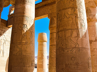 Luxor Temple illuminated at sunset, featuring ancient columns, pharaonic statues, and detailed hieroglyphics along the Nile R