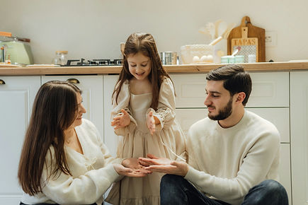 Two parents smiling at their young daughter standing on a kitchen counter