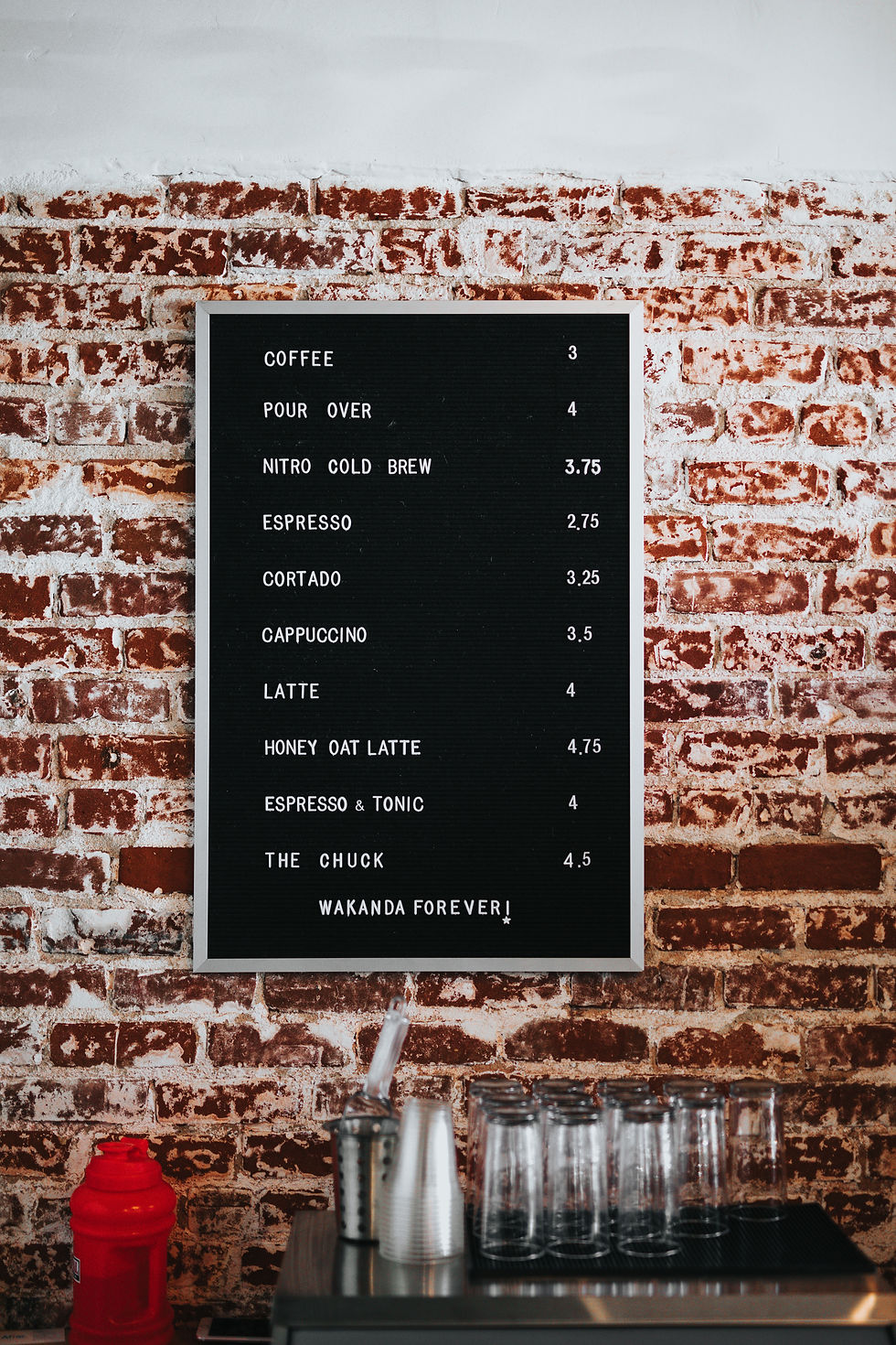 a menu at a local coffee shop hanging on a brick wall