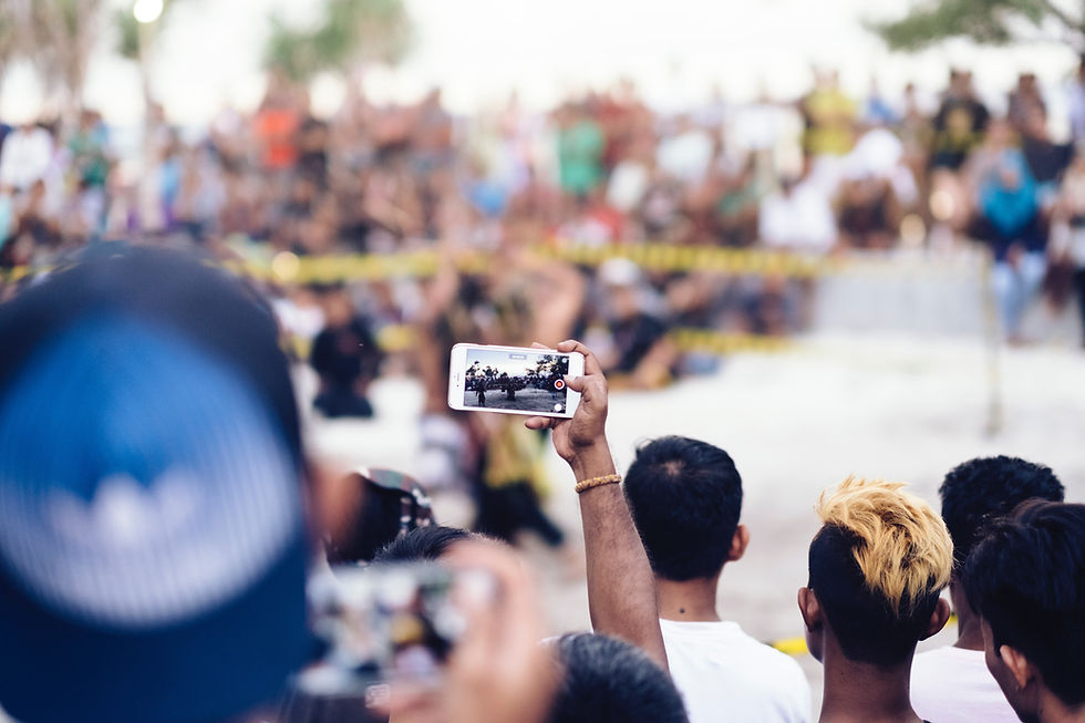 Crowd around police barricade while filming with cell phones.