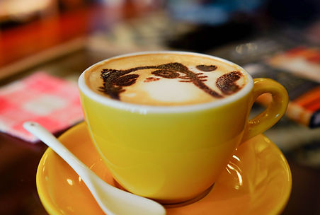 a yellow coffee cup with latte art resembling a cat