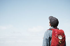 Man with backpack and a hat looking at the sky