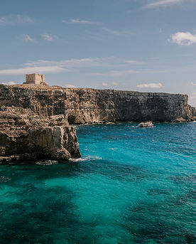The deep blue Mediterranean Sea meets dramatic limestone cliffs along the rugged coastline of Malta.