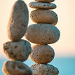 Balanced stone towers by a tranquil sea, symbolizing the deliberate harmony and energetic balance cultivated in group coaching