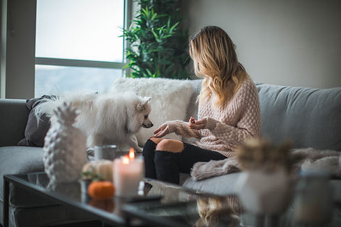 woman a couch with her dog and a candle on the table