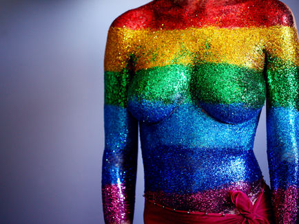 Body with breasts covered in glitter in rainbow colours