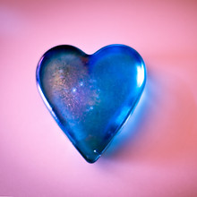 pink background with a blue glass heart shaped object