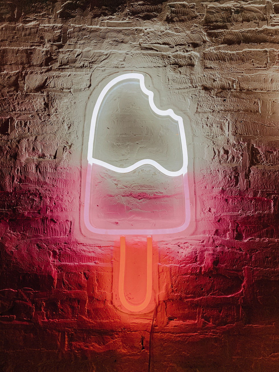Glowing neon sign of a pink & white popsicle with one bite taken out of the top