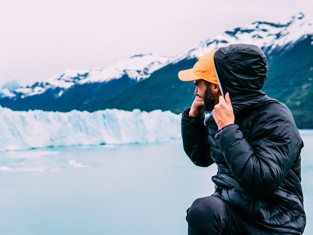 Escursionista con cappuccio e cappello che guarda contemplativo il Ghiacciaio Perito Moreno in Argentina.